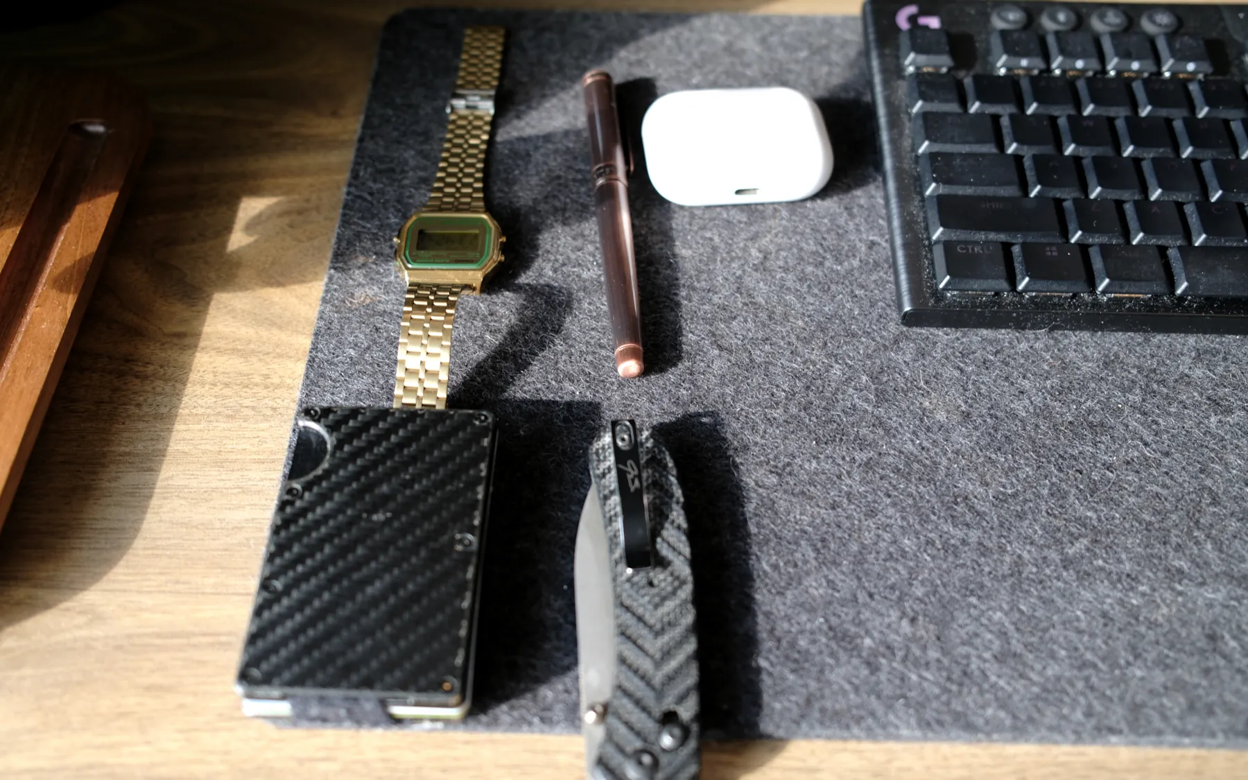 Casio watch, copper pen, earbuds case, carbon wallet and knife